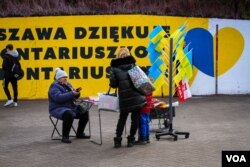 FILE - A Polish woman sells Ukrainian flags at Warsaw Centrum Subway Station, Warsaw, Poland, April 6, 2022. Poland has offered its support for Ukrainians who have fled their country. (Tommy Walker/VOA)