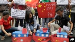 FILE - Filipino student activists set fire mock Chinese ships to protest recent island-building and alleged militarization by China off the disputed Spratlys group of islands in the South China Sea, in Manila, March 3, 2016. 