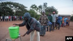 FILE - People queue to wash their hands to protect against the coronavirus before lining up to vote at a polling station, in Lilongwe, Malawi, June 23, 2020. The COVID pandemic has led to a spike in suicides in the southeastern African country. 