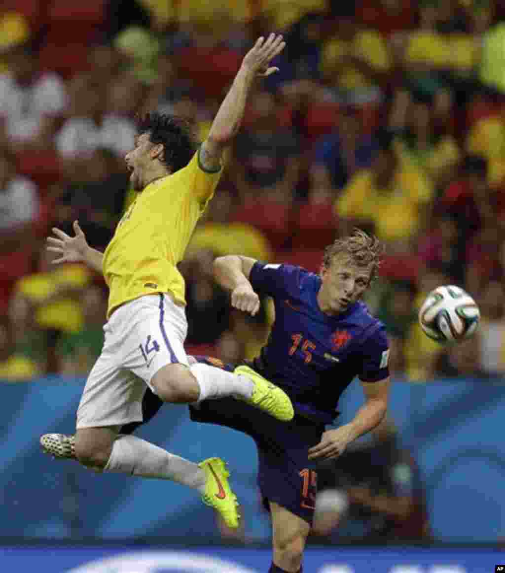 Brazil's Maxwell, left, and Netherlands' Dirk Kuyt leap in the air after attempting to head the ball during the World Cup third-place soccer match between Brazil and the Netherlands at the Estadio Nacional in Brasilia, Brazil, Saturday, July 12, 2014. (AP