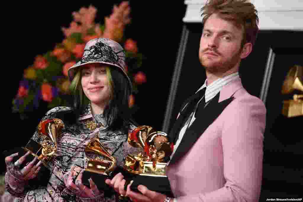 Finneas, left, and Billie Eilish pose in the press room with the awards for best song written for visual media and record of the year at the 63rd annual Grammy Awards at the Los Angeles Convention Center, California, March 14, 2021. 