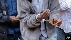 FILE - Three men walk in handcuffs after being arrested as organizers of an opposition demonstration, which was dispersed by police firing in the air, in Jenda, Burundi, June 12, 2015. 