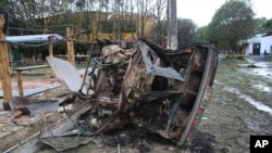 ARCHIVO - Un automóvil destruido por la explosión de un coche bomba cercano se encuentra en la carretera en Saravena, Arauca, Colombia, el jueves 20 de enero de 2022.