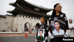資料照：一名脫北者母親和她的女兒手持另外一名在逃亡路上去世的脫北者母親與其兒子的照片，在南韓首爾為母子二人舉行葬禮。 （2021年9月21日）