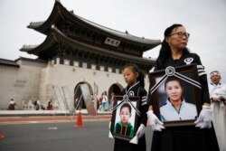 FILE - A girl and her North Korean defector mother hold portraits of a 42-year-old defector mother and her 6-year-old son who were found dead of starvation, during their funeral in Seoul, South Korea, Sept. 21, 2019.