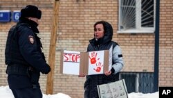 Офіцер міліції йде до жінки, яка тримає плакат біля пам’ятника Лесі Українці у Москві, Росія. Фото: AP