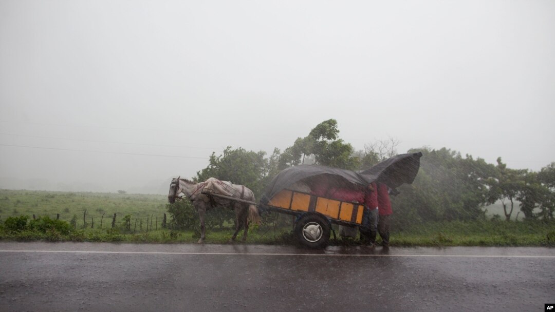 People take cover under a plastic tarp during heavy rain after the San Cristobal volcano spewed smoke and ash, near Chinandega, Nicaragua, Sept. 8, 2012. 
