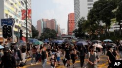 Demonstrators wearing face masks walk down a street during a protest in Hong Kong, Oct. 12, 2019.