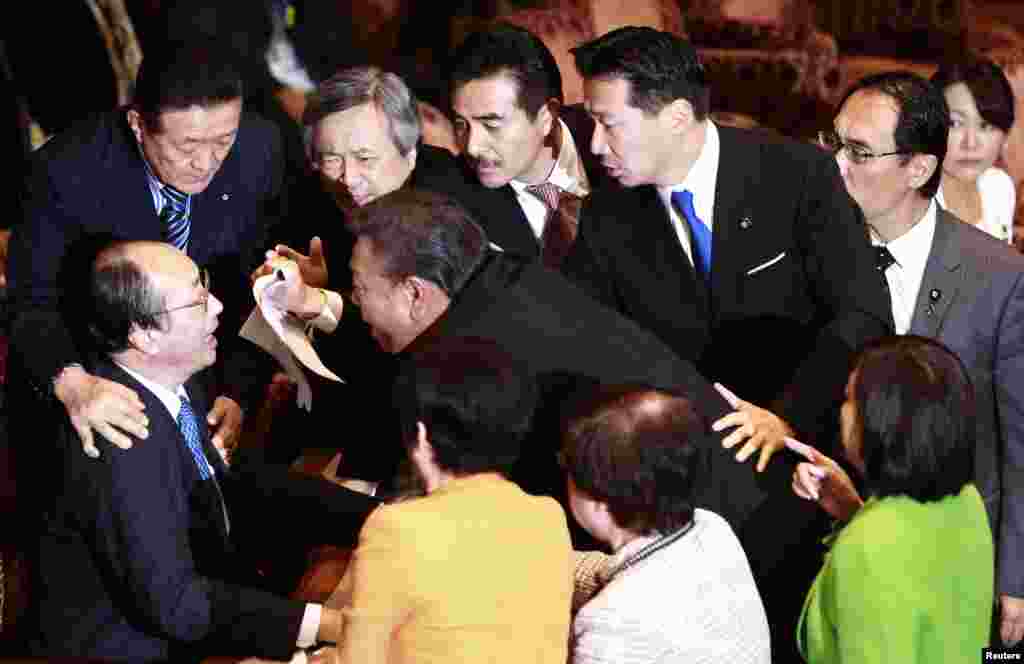 Masaharu Nakagawa (bottom, L), chairman of the Upper House Special Committee on National Security, is surrounded by lawmakers during a vote on a state secrets act at the parliament in Tokyo, Japan. 