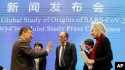 ماریون کوپمانس (راست) و پیتر بن امبارک (وسط)، دانشمندان تیم پژوهشی سازمان بهداشت جهانی، با همکاران چینی خود وداع می‌کنند - ۹ فوریه ۲۰۲۱