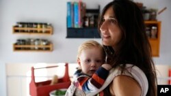 FILE - Fulvia Serra carries her 1-year-old baby, Sebastiano, at home in Fort Collins, Colo., Oct. 20, 2016. Serra, originally from Italy, and her husband, Scott, are raising their son vegan.