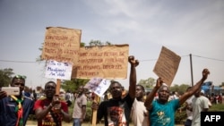 FILE - Demonstrators hold placards in a march to protest the security situation worsening and asking for a response to jihadist attacks, in Ouagadougou, on July 3, 2021. 