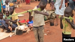 Martin Andrea, 10, and a friend play with toy guns made from long grass reeds at a displaced persons camp protected by U.N. peacekeepers in Wau, South Sudan, Sept. 4, 2016.