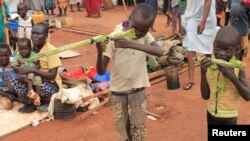 FILE - Boys play with toy guns made from long grass reeds at a displaced persons camp protected by U.N. peacekeepers in Wau, South Sudan, Sept. 4, 2016.