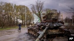 A man rides his bicycle next to a destroyed Russian tank in Chernihiv, Ukraine, on April 21, 2022.