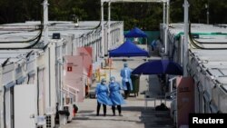 FILE - Workers wearing personal protective equipment work at a COVID-19 isolation facility, amid the pandemic, in Hong Kong, March 21, 2022. 