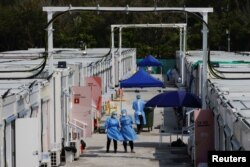 Workers wearing personal protective equipment work at a COVID-19 isolation facility, amid the pandemic, in Hong Kong, March 21, 2022.