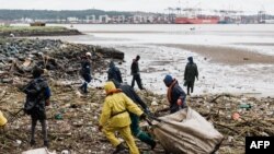 FILE - Volunteers clean up massive debris at the Durban harbor following heavy rains, mudslides and rain and winds in Durban, on Apr. 16, 2022 