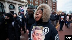 FILE: A woman wears a sweater with an image of Patrick Lyoya as protesters march for Lyoya, a Black man who was fatally shot by a police officer, in downtown Grand Rapids, Michigan, April 16, 2022.