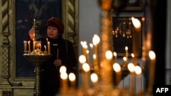 A woman lights a candle at the Svyato-Pokrovsky church in Kramatorsk, eastern Ukraine, during mass, April 17, 2022, amid Russia's invasion of its neighbor.