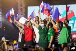 Mantan senator Ferdinand "Bongbong" Marcos Jr., kiri tengah, dan pasangannya Wali Kota Davao City Sara Duterte, kanan tengah, mengibarkan bendera Filipina saat pengumuman pencalonannya sebagai presiden, di Philippine Arena, Filipina. (Foto: AP)