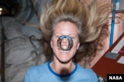 In this file photo, NASA astronaut Karen Nyberg watches a water bubble float freely between her and the camera, showing her image refracted in the droplet. (Image Credit: NASA)