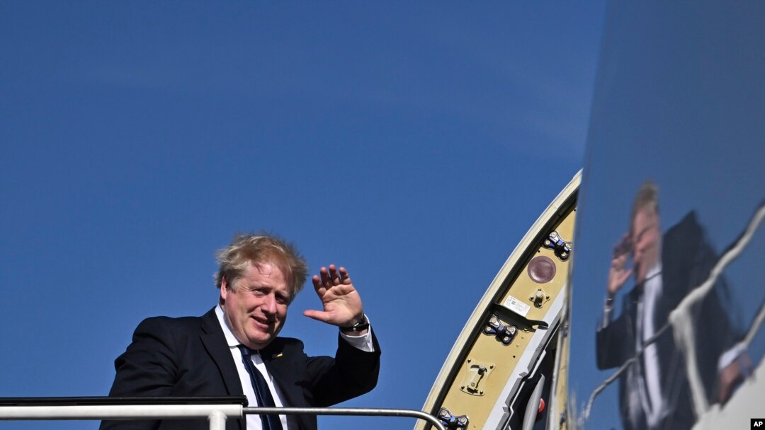Britain's Prime Minister Boris Johnson waves as he boards a plane at Stansted Airport, northeast of London, April 20, 2022, for a visit to India. 