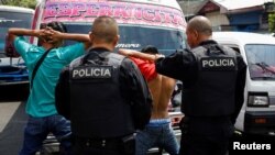 Policías registran a dos hombres en un autobús después de que el Congreso de El Salvador aprobara el martes un proyecto de ley que criminaliza la publicación de mensajes de las pandillas, incluso en medios de comunicación, en San Salvador, El Salvador, el 7 de abril de 2022.