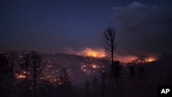 FILE - Fire burns along a hillside in the Village of Ruidoso, N.M., April 13, 2022.