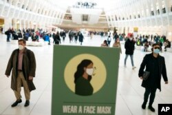 Mass transit riders wear masks as they commute in the financial district of lower Manhattan, in New York, April 19, 2022, after a federal judge ruled to strike down a national mask mandate.