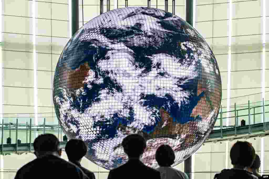 Reporters look at the Geo-Cosmos, the world&#39;s first spherical display made of organic electroluminescent panels showing a high-resolution model of the Earth, with 10,362 LED panels during a media preview at the Miraikanon, the National Museum of Emerging Science and Innovation in Tokyo, Japan.
