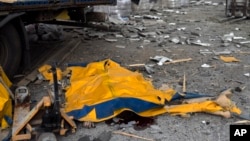 The body of a man is covered by a tarp from a damaged truck following a Russian bombing of a factory in Kramatorsk, in eastern Ukraine, Apr. 19, 2022. 