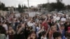 FILE - Young protesters cast the light of their cellphones during an anti-war rally in memory of the victims of fighting in Ukraine, in front of Ukrainian Embassy in Tbilisi, Georgia, April 3, 2022.