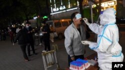 Esta foto tomada el 19 de abril de 2022 muestra a un residente que se somete a una prueba de ácido nucleico para detectar el coronavirus COVID-19 en Wuhan, en la provincia central china de Hubei. 