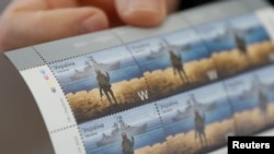 Ukrainian postal service chief Igor Smelyansky holds postage stamps showing a Ukrainian service member's gesture toward a Russian warship at postal service headquarters in Kyiv, April 14, 2022.