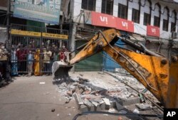 Sebuah buldoser meruntuhkan bangunan di daerah Jahangirpuri barat laut New Delhi, India, Rabu, 20 April 2022. (AP Photo/Altaf Qadri)