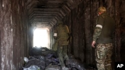 Servicemen of the Donetsk People's Republic militia look at bodies of Ukrainian soldiers placed in plastic bags in a tunnel. (AP Photo/Alexei Alexandrov, File)