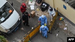 Health workers wearing protective gear cross a checkpoint during a COVID-19 lockdown in the Jing'an district of Shanghai, China, April 16, 2022. 