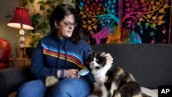 Tara Kramer sits in her apartment with her cat Busy, April 8, 2022, in Des Moines, Iowa. More of the roughly 40 million Americans who get help buying food through the federal SNAP program are seeing their benefits plunge even as the nation struggles with 