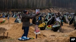 Alla Prohonenko, 53, touches a photo of her father, Volodymyr Prohonenko, following his funeral at a cemetery in Irpin, on the outskirts of Kyiv, April 21, 2022. Prohonenko was killed when Russian troops were advancing on Kyiv. 