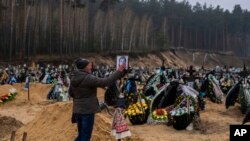 Alla Prohonenko, 53, touches a photo of her father, Volodymyr Prohonenko, during his funeral in Irpin, cemetery on the outskirts of Kyiv, on April 21, 2022. Proponenko died during the Russian occupation. 