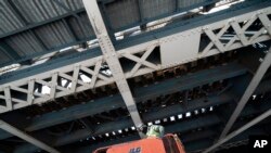 A painter works on steel support beams underneath the Manhattan Bridge, part of New York's aging infrastructure, April 6, 2021.