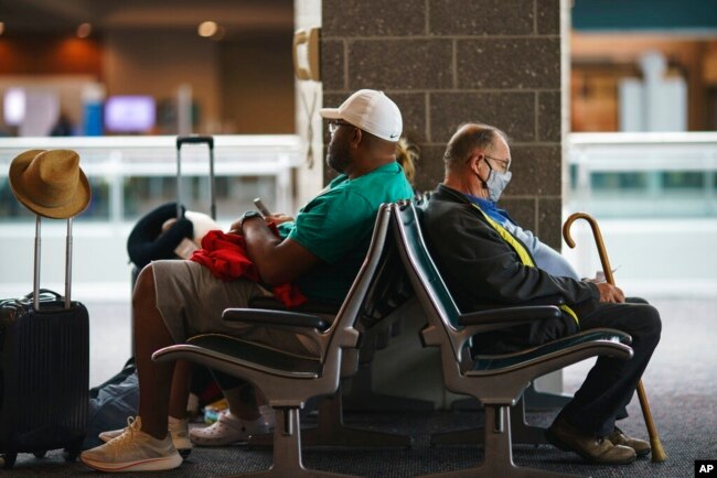 Travelers sit in a waiting area at Rhode Island T.F. Green International Airport in Providence, R.I., April 19, 2022. A federal judge's decision to strike down a national mask mandate was met with cheers by some and concern by others.