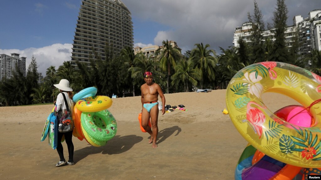 FILE - Vendors selling swimming accessories walk on Sanya Bay beach in Sanya, Hainan province, China November 26, 2020. (REUTERS/Tingshu Wang/File Photo)