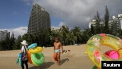 FILE PHOTO: Vendors selling swimming accessories walk on Sanya Bay beach in Sanya, Hainan province, China November 26, 2020. REUTERS/Tingshu Wang/File Photo