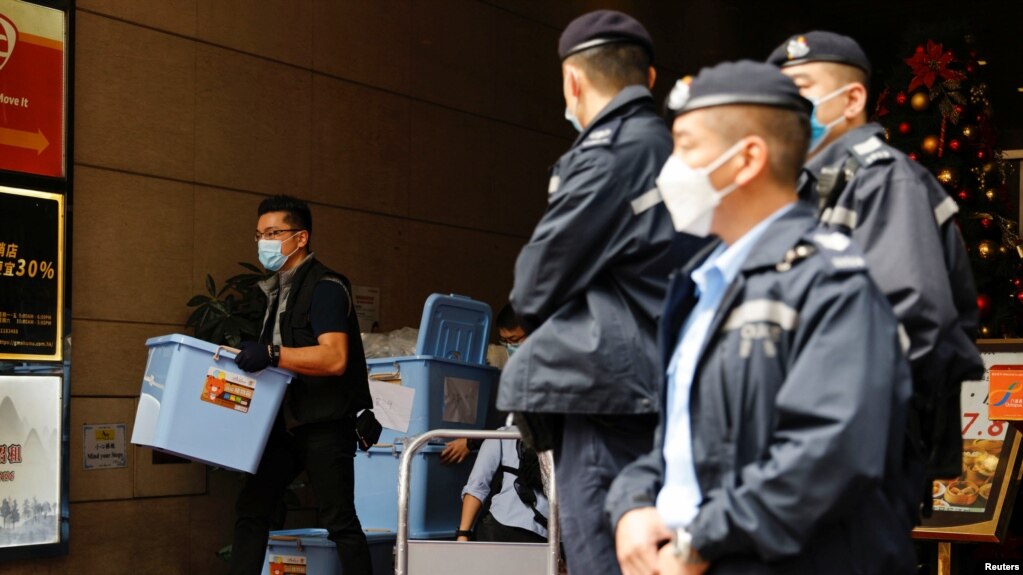 资料照：2021年12月29日，香港一名警察在搜查了《立场新闻》办公室后收集了一箱证据。（路透社）(photo:VOA)