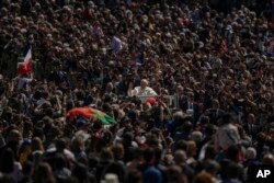 Paus Fransiskus dengan mobil kepausannya melewati kerumunan umat pada akhir misa Minggu Paskah Katolik yang dipimpinnya di Lapangan Santo Petrus di Vatikan, 17 April 2022. (Foto: AP)