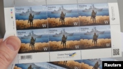 一位男士在基辅邮政局总部拿着一版反映一名驻蛇岛乌军士兵向俄罗斯军舰表示不屈的邮票。邮票上的那艘导弹巡洋舰“莫斯科娃”号现已沉没。(2022年4月14日)