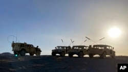 FILE: Army vehicles park on the ridge as soldiers from the 2nd Brigade, 1st Cavalry Division, prepare to attack the enemy during a training exercise at the National Training Center at Fort Irwin, Calif., April 12, 2022.