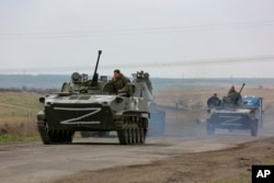 Russian military vehicles move on a highway in an area controlled by Russian-backed separatist forces near Mariupol, Ukraine, April 18, 2022.